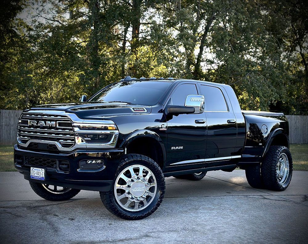 Black Ram 3500 dually truck with custom wheels parked on pavement.