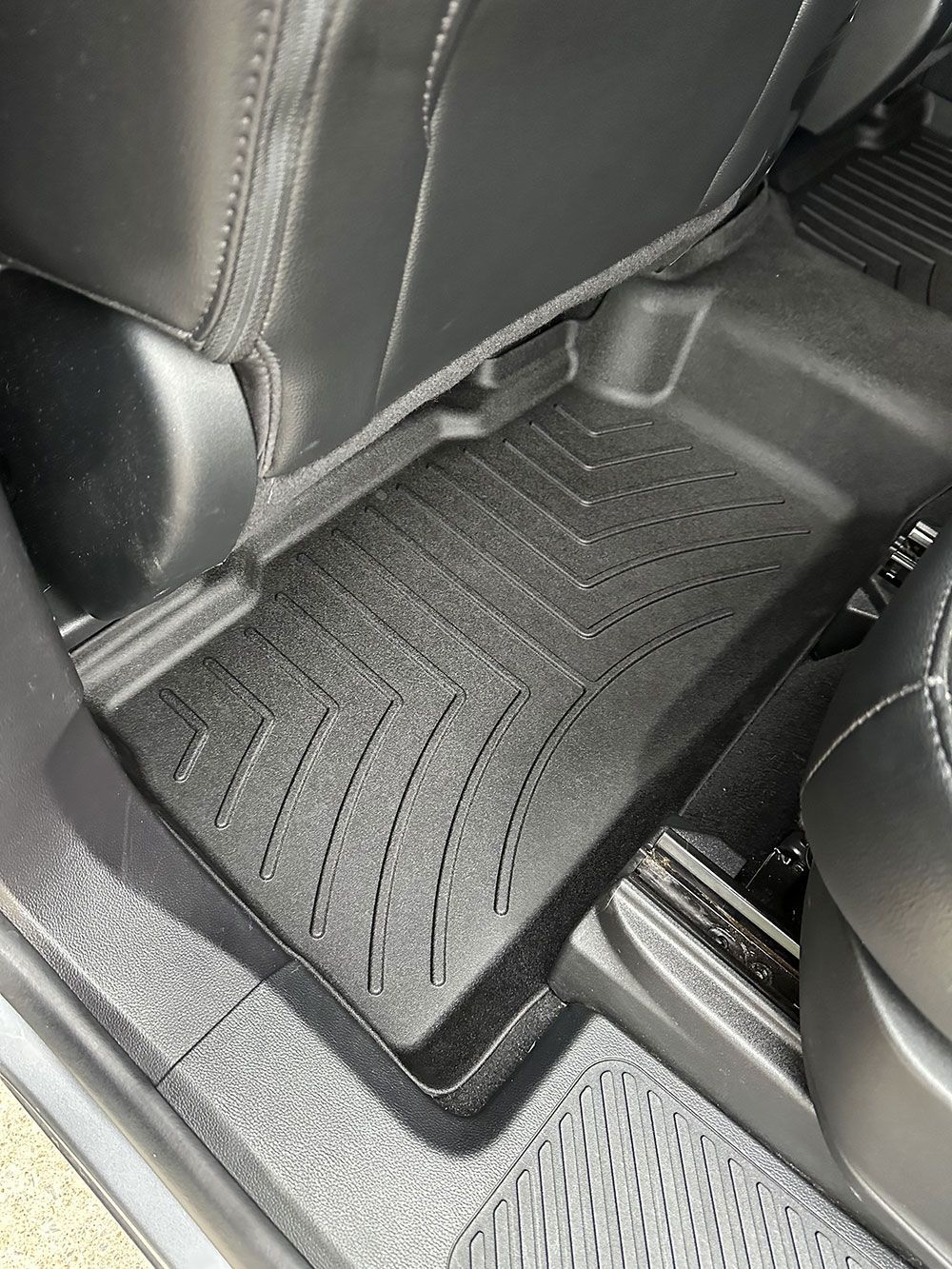 Black rubber floor mat in a car, protecting the carpet.