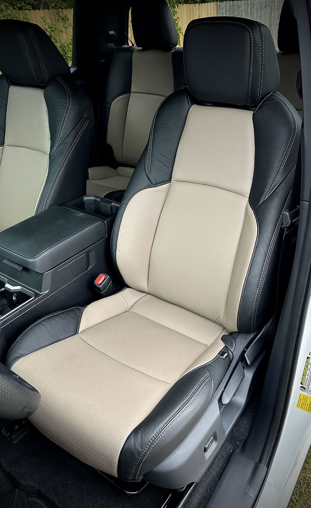 Car interior: black and tan leather seats, center console.