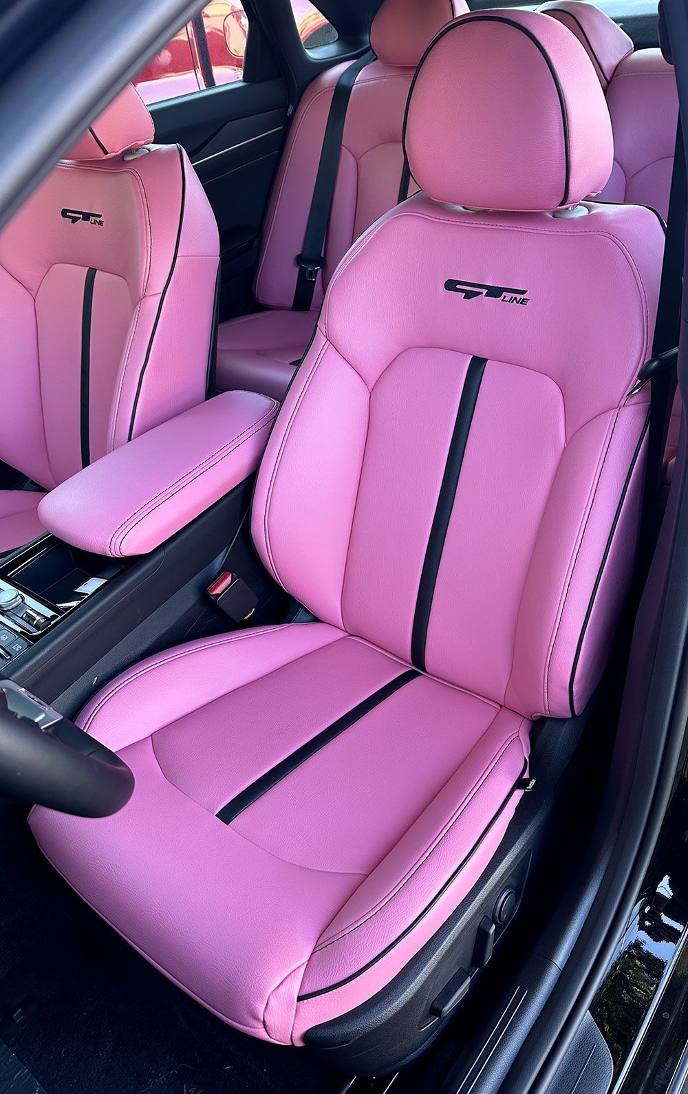 Pink car seats with black accents inside a vehicle.