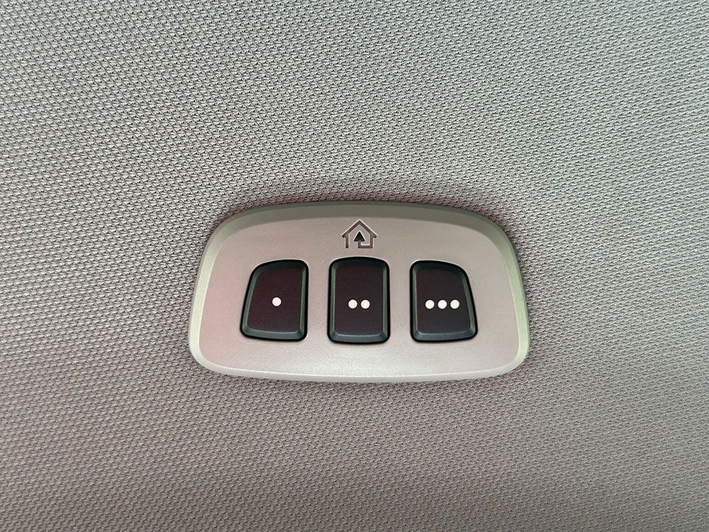 Overhead garage door opener buttons: up arrow and three numbered buttons. Gray panel on a textured ceiling.