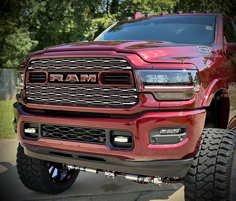 Red Ram truck with custom grill, lifted, and large tires.