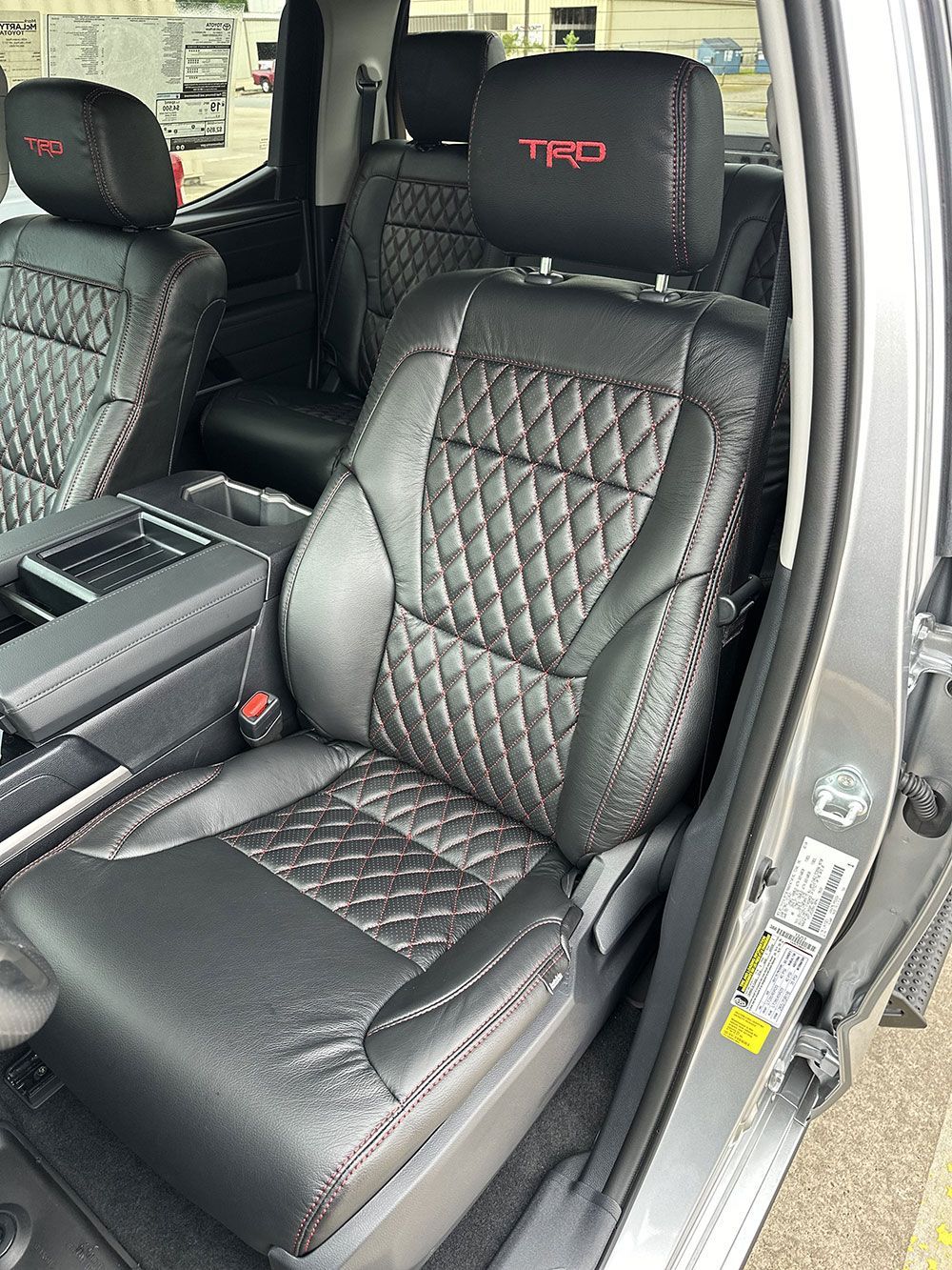 Black leather car seats with red stitching and TRD headrest logo.