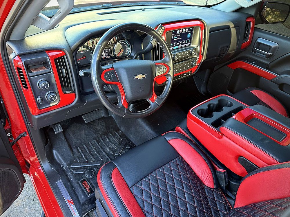 Red and black custom truck interior with diamond-stitched seats, red trim on dashboard, steering wheel and console.