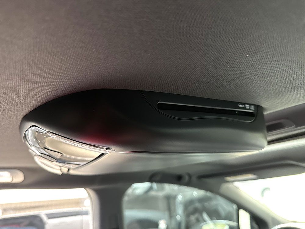 Black overhead console in a car interior with lights and a card slot.