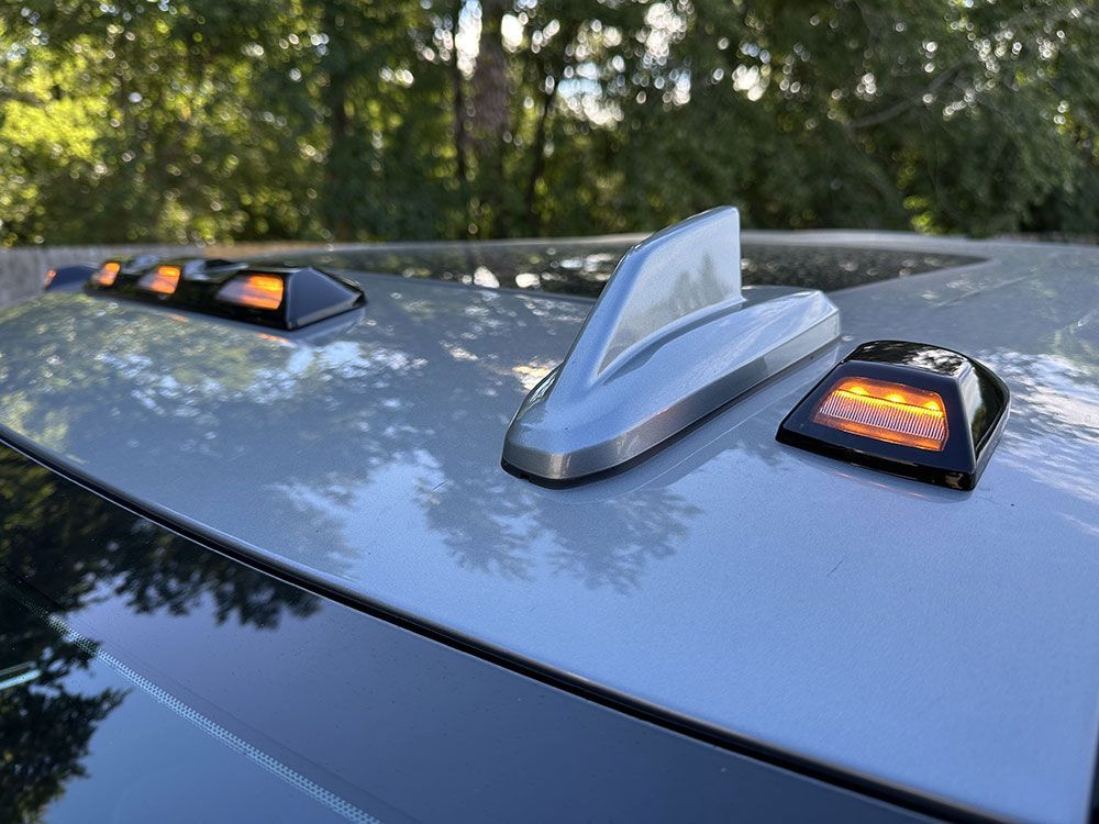 Silver car roof with antenna and amber marker lights.