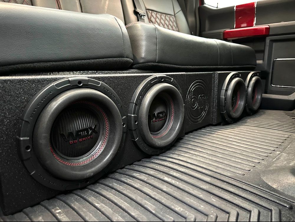 Black car interior with a custom subwoofer box under the back seat.
