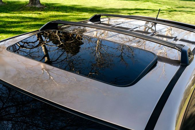 Sunroof on car with reflections of trees on a sunny day.