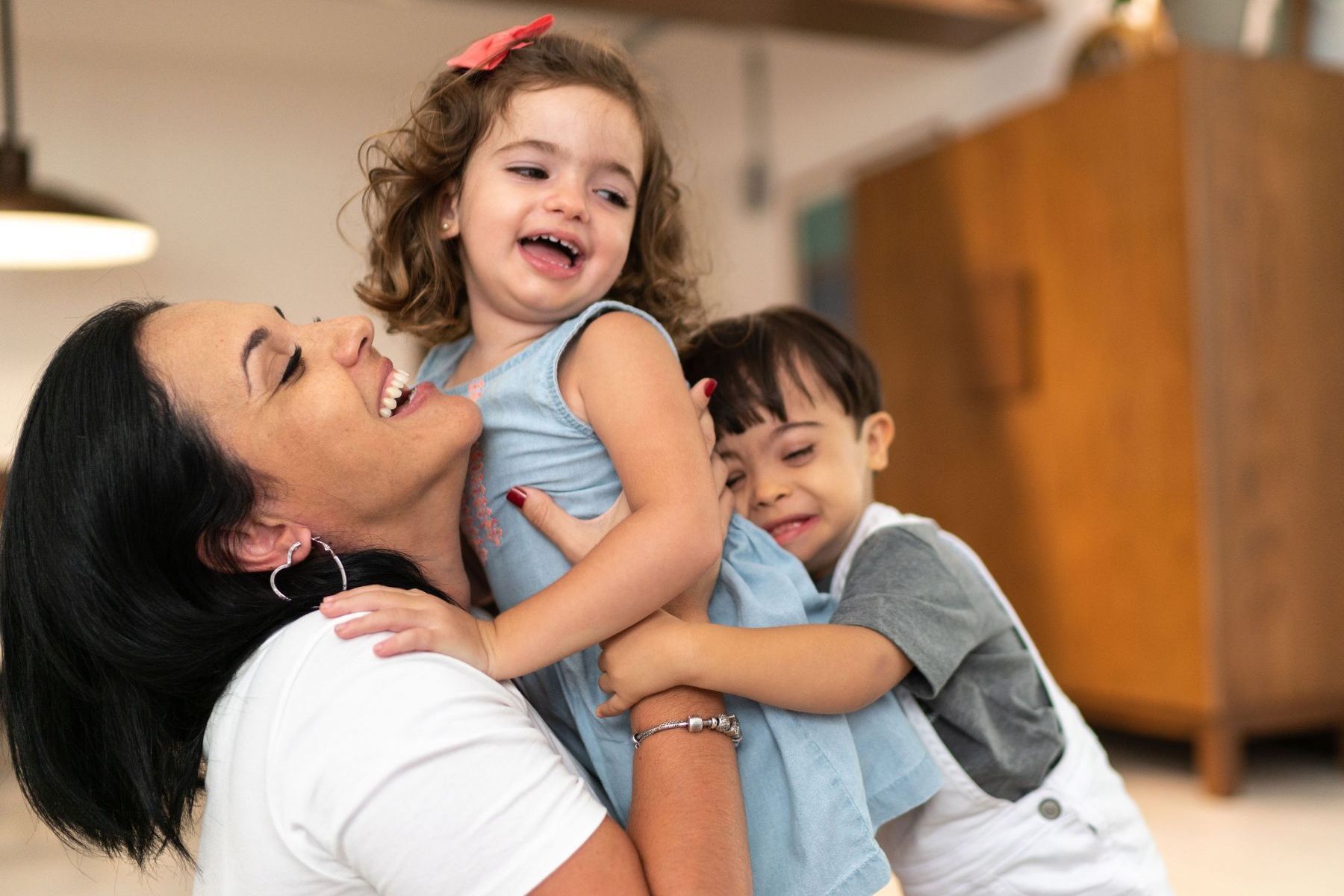 A woman is holding two children in her arms.