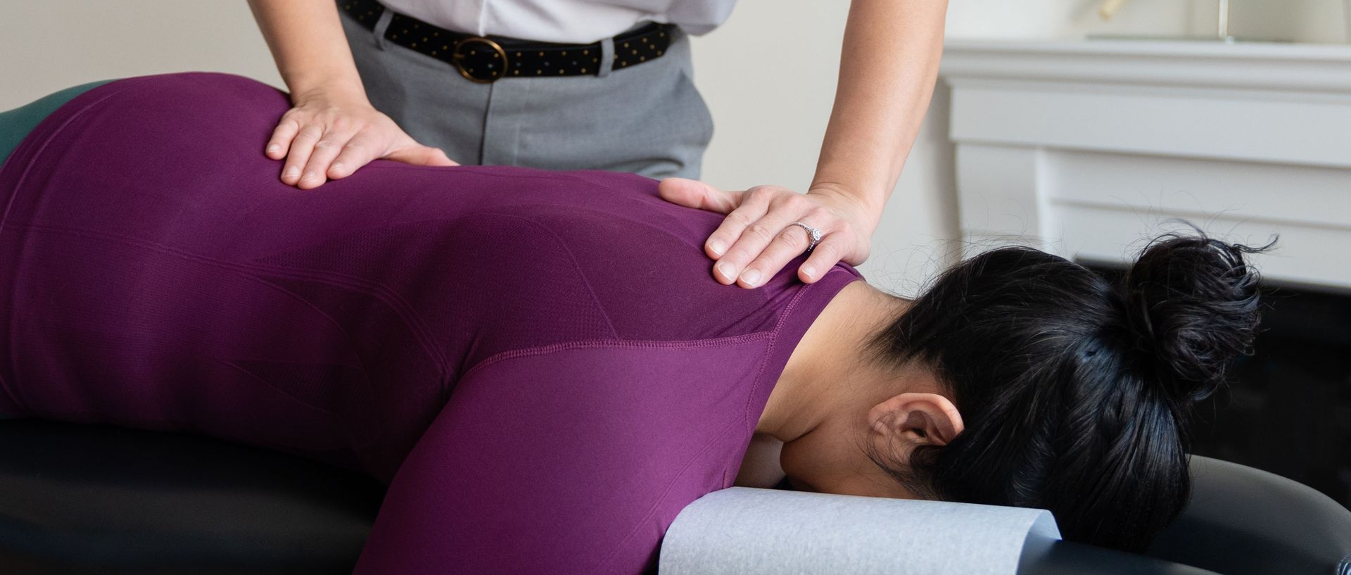 A chiropractor adjusting a patient's back on a treatment table, indoors.