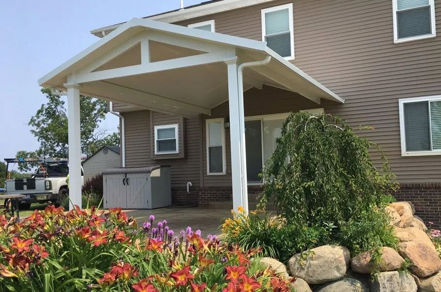 A house with a porch and flowers in front of it.