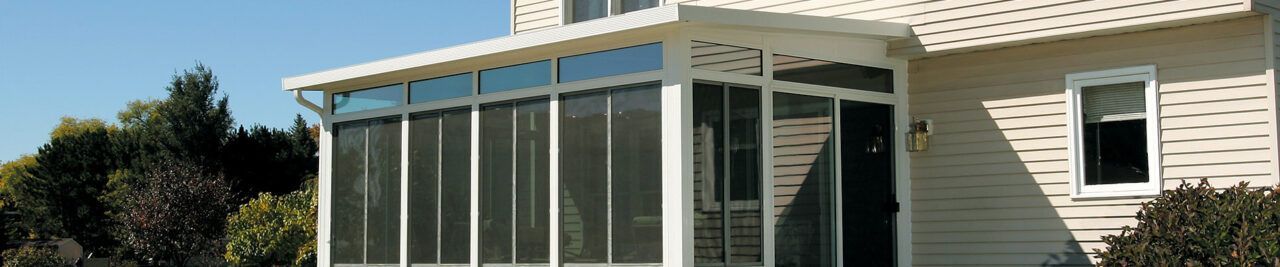 A white house with a screened in porch on the side of it.