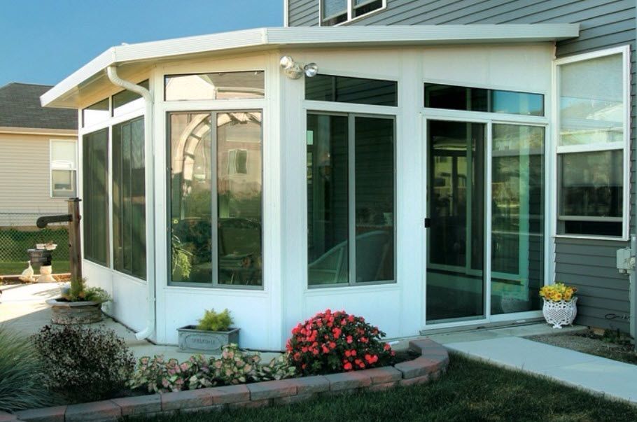 A house with a screened in porch and flowers in front of it
