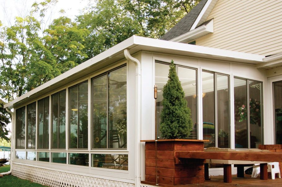 A sunroom with a lot of windows on the side of a house.