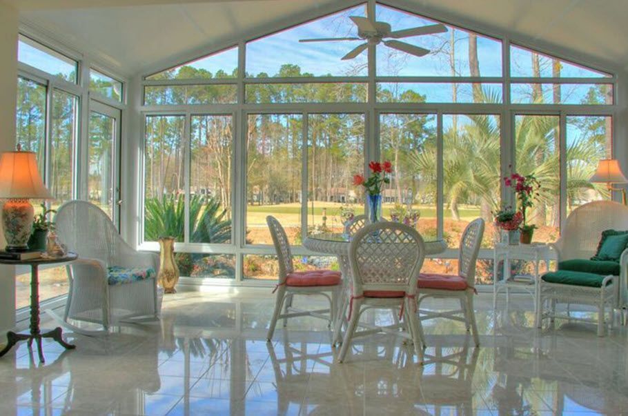 A sunroom with a table and chairs and a ceiling fan