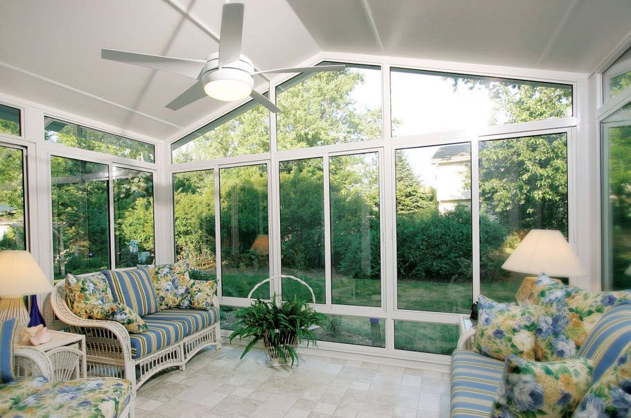 A sunroom with a couch and chairs and a ceiling fan