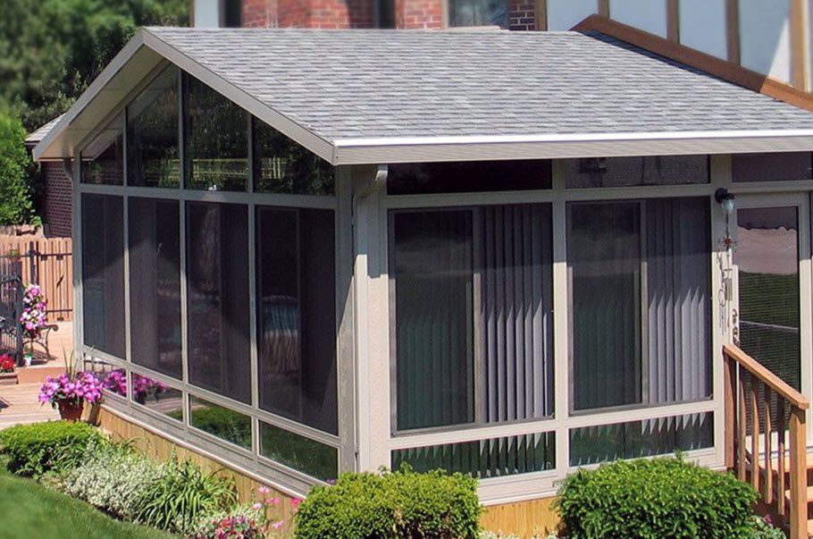 A screened in porch with a roof and lots of windows