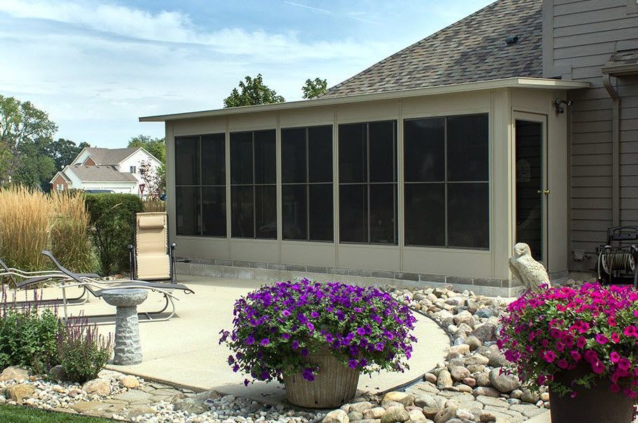 A screened in porch with purple flowers in front of it