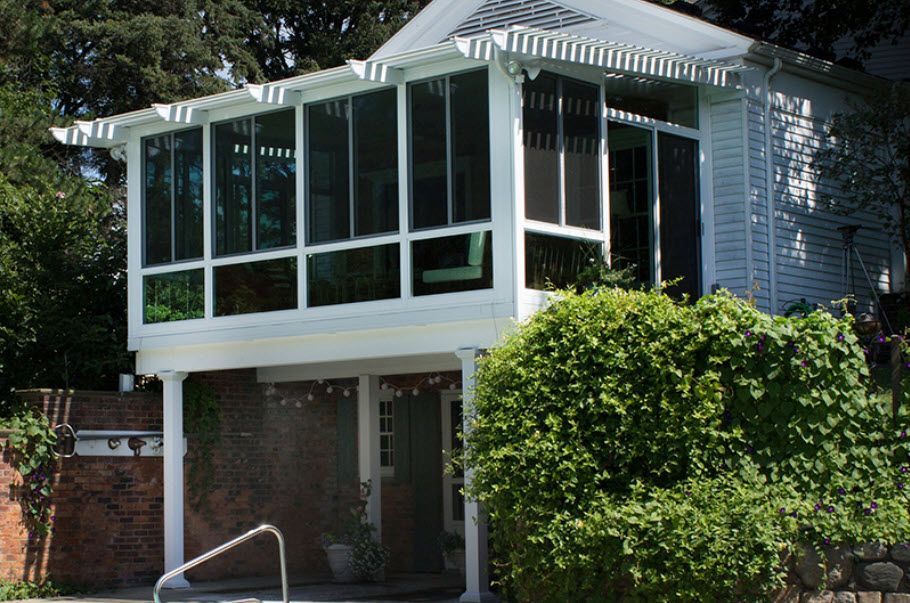 A white house with a screened in porch and lots of windows