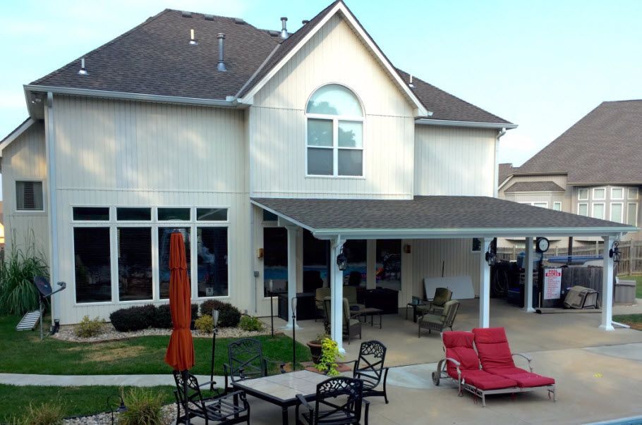 A large white house with a covered patio with a table and chairs