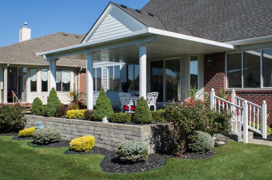 A house with a covered porch and a brick wall in front of it