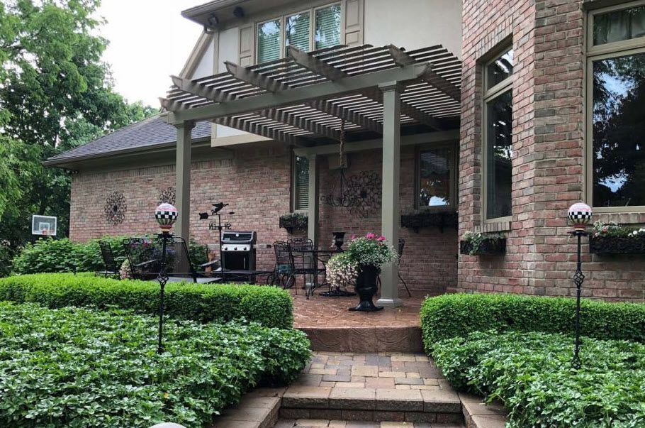 A brick house with a pergola and a patio in front of it.