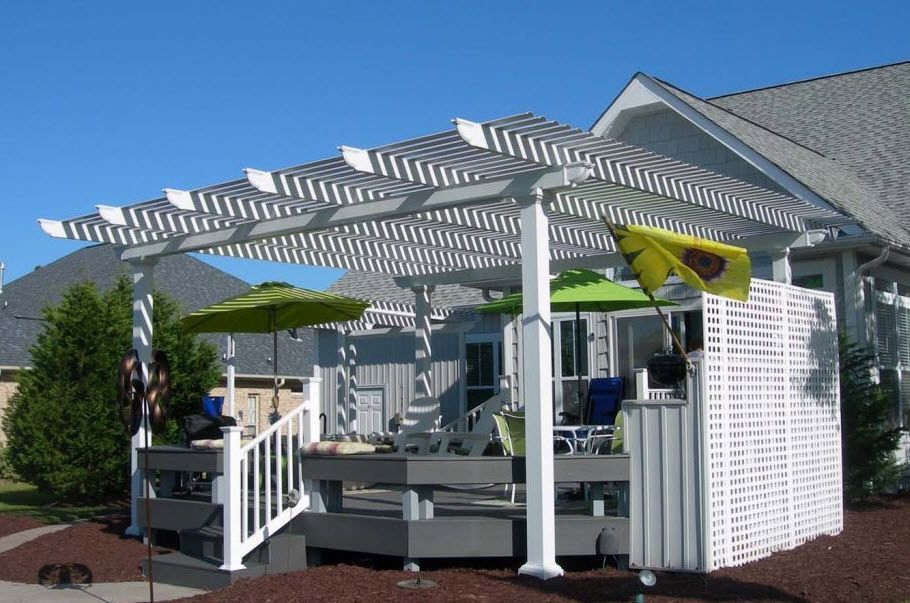 A house with a pergola and umbrellas in front of it