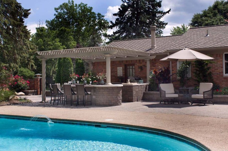 A large swimming pool in front of a brick house