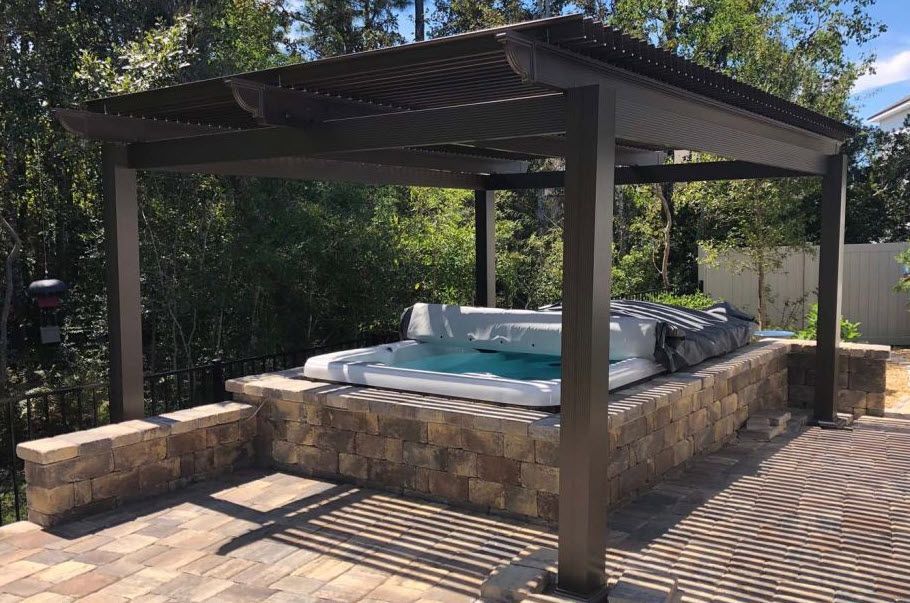 A hot tub is under a pergola in a backyard.