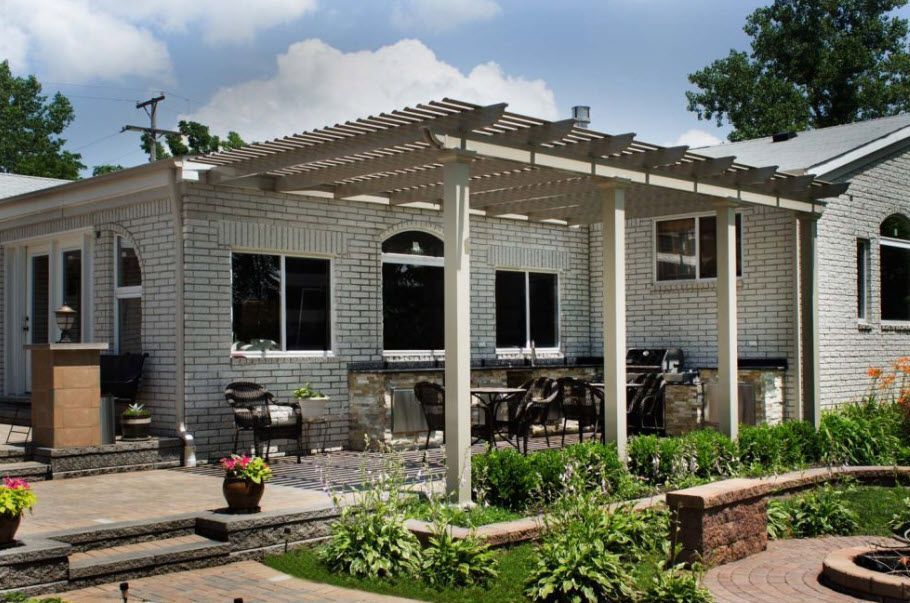 A white brick house with a pergola in the backyard