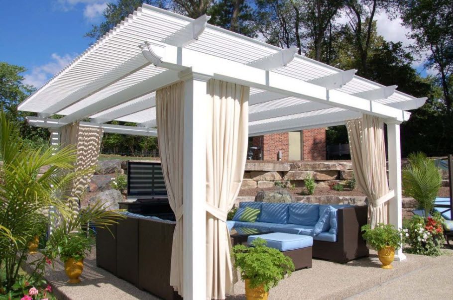 A white pergola with curtains and a couch underneath it.