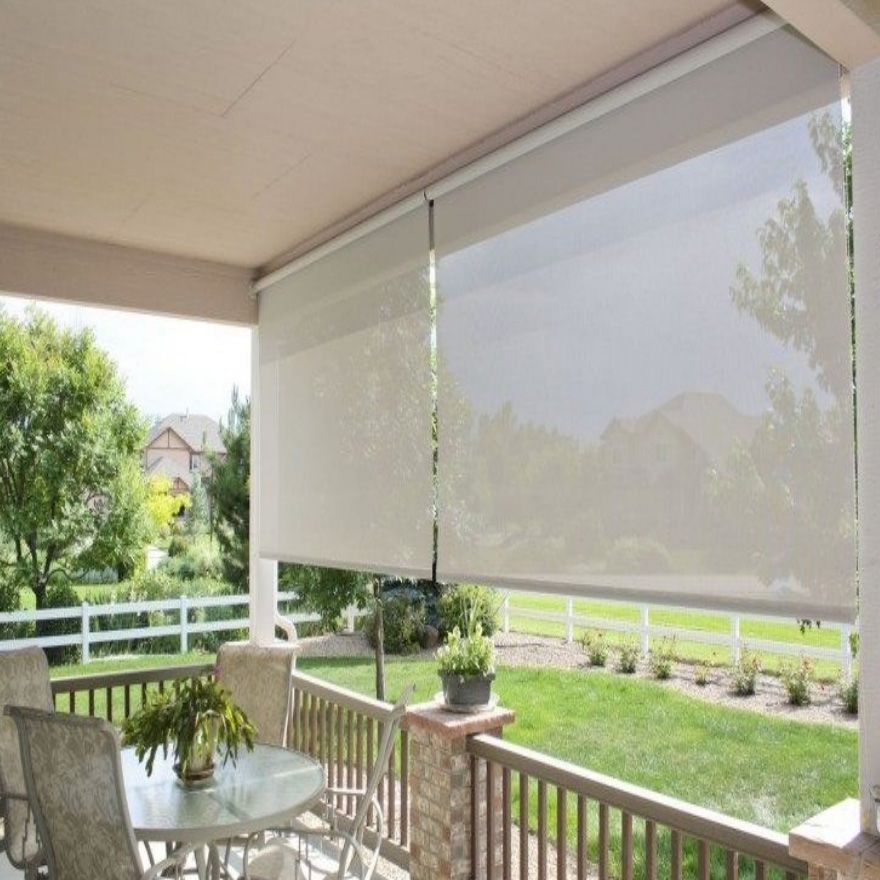 A porch with a table and chairs and a fence in the background