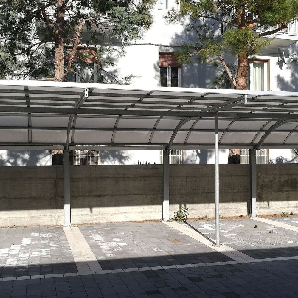A carport with a clear roof in front of a building