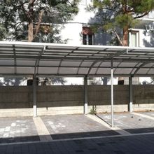 A carport with a clear roof in front of a building