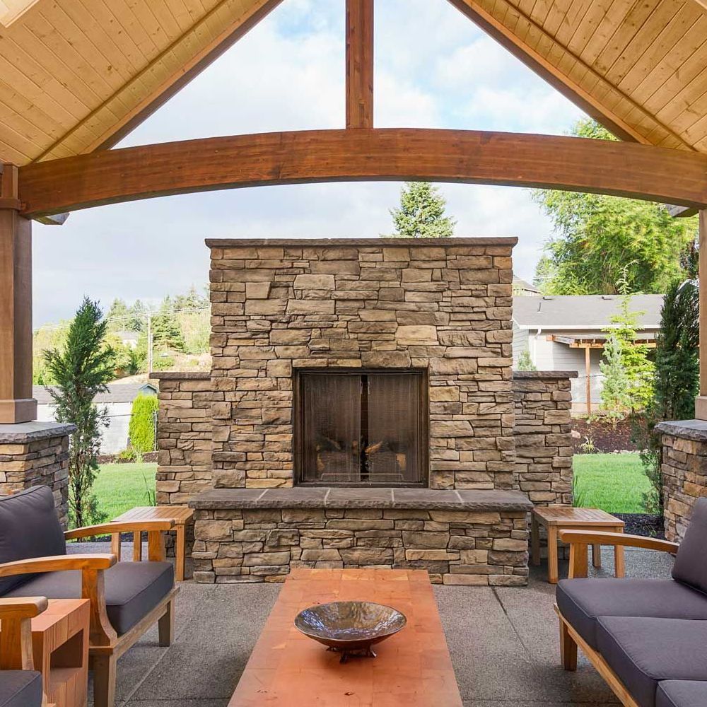 A living room with a stone fireplace and a wooden ceiling