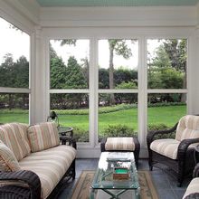 A screened in porch with a couch and chairs