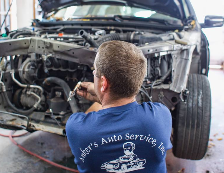 Mechanic working on a car’s exposed front end in an auto repair shop