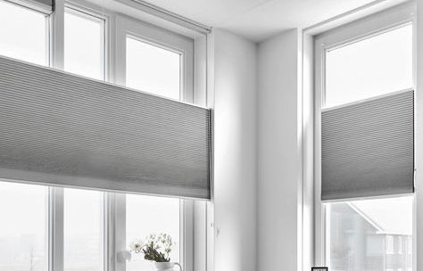 White windows with light gray honeycomb shades partially covering the glass.