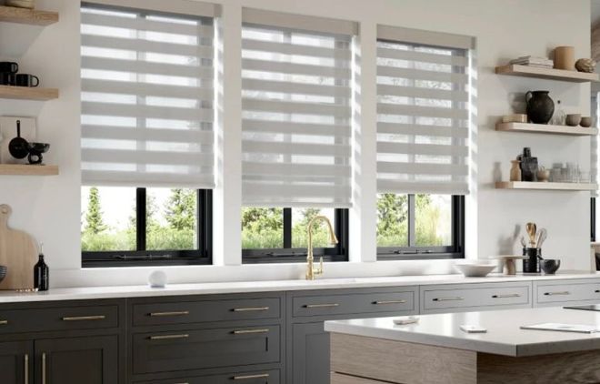 Kitchen with three large windows, grey cabinets, white countertops, and light grey zebra blinds.