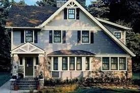 Two-story house with stone facade and gray siding, featuring a gabled roof and multiple windows.