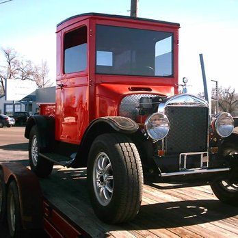 An old red truck is parked on a wooden deck