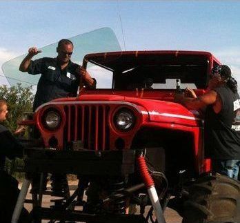 A group of men are working on a red jeep