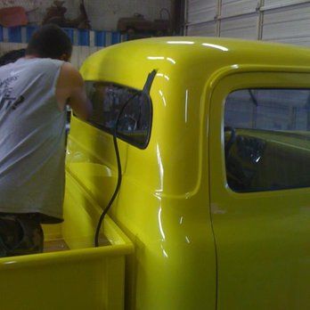 A man is working on a yellow truck in a garage.