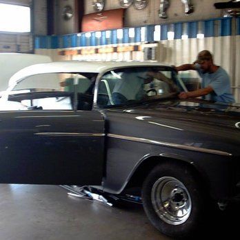 A man is working on a black car in a garage