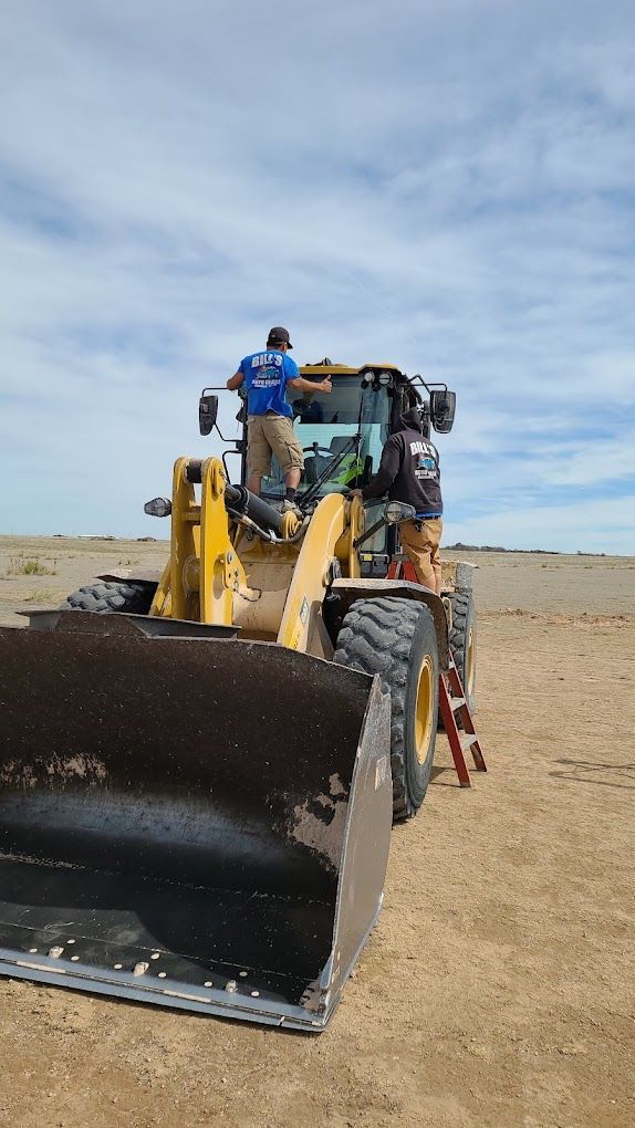 A man is driving a bulldozer on a dirt field.