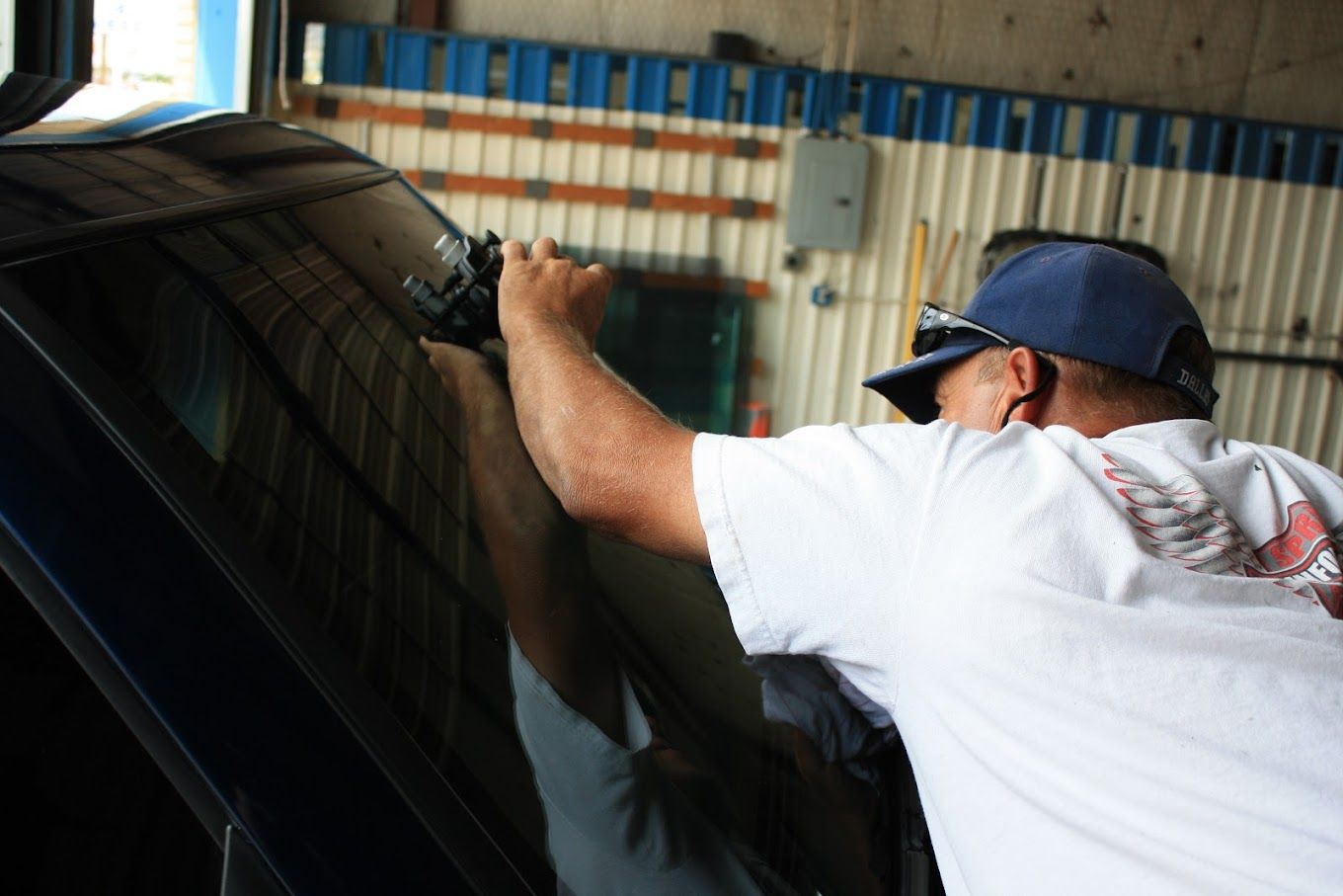 A man in a white shirt is working on a car window