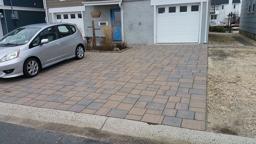 A silver car is parked in a driveway in front of a house