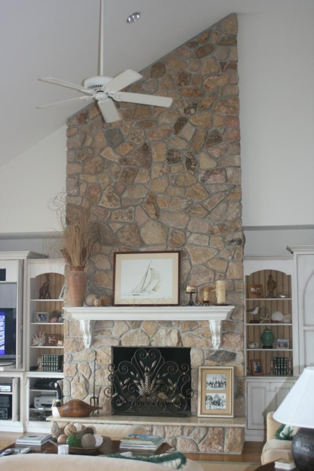 A living room with a fireplace and a ceiling fan