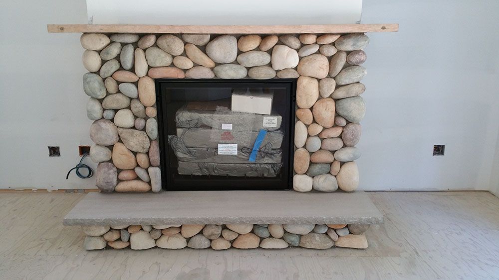 A stone fireplace is being built in a living room
