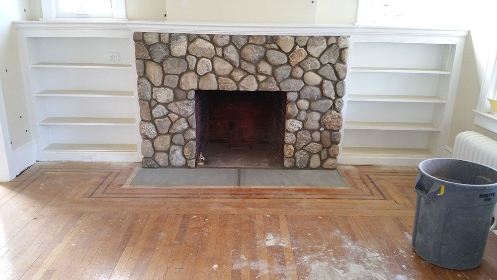 A living room with a stone fireplace and shelves